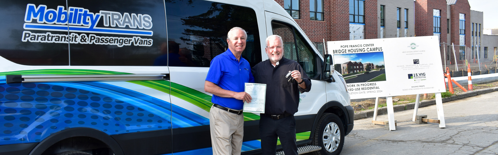Dave Brown, General Manager of MobilityTRANS, presenting the title and keys of a new Ford E-Transit to Fr. Tim McCabe, Executive Director of the Pope Francis Center, in a handover event on Tuesday.